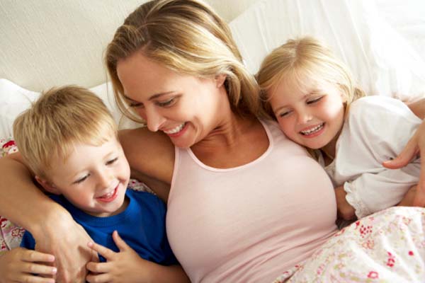 Mother And Children Relaxing Together In Bed Because Domestic Violence was Prevented
